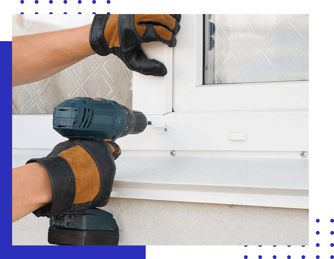 A person holding a drill next to a window.