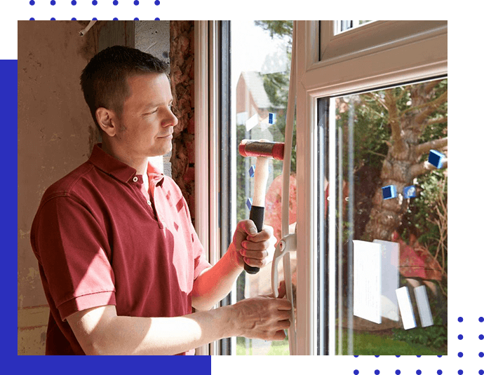A man holding a hammer and looking out of the window.